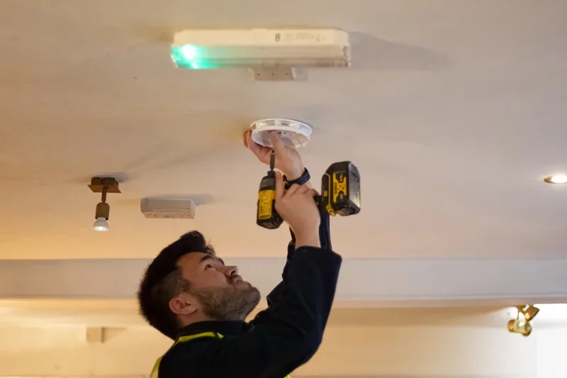 Recall SW technician installing smoke alarm for fire safety compliance